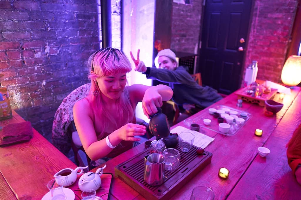 Tea ceremony with vibrant pink and purple lighting, a person pouring tea